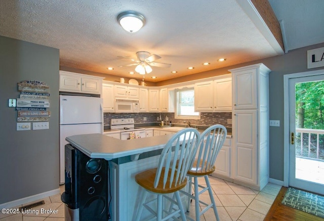 kitchen with light tile patterned flooring, white appliances, backsplash, and baseboards