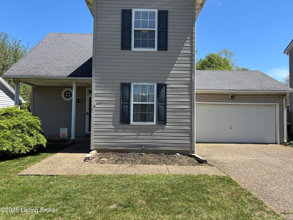 traditional-style home with concrete driveway, a front yard, an attached garage, and a shingled roof