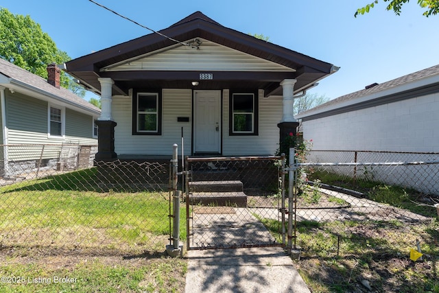 shotgun-style home with a front lawn, a fenced front yard, covered porch, and a gate