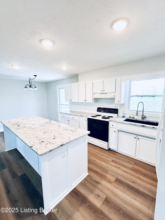 kitchen featuring electric stove, a textured ceiling, white cabinetry, and a sink
