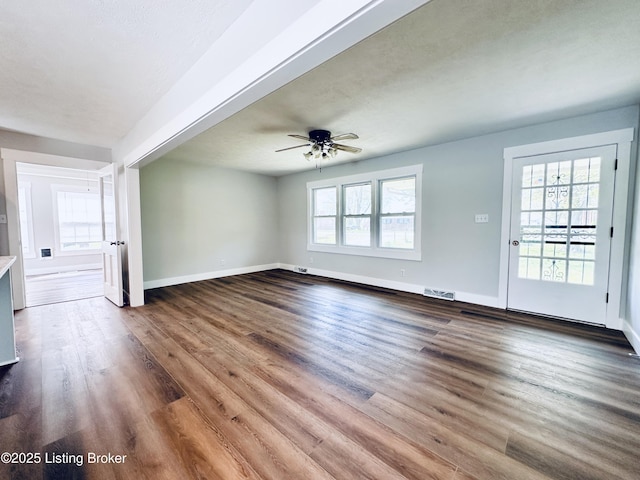 unfurnished living room with baseboards, visible vents, wood finished floors, and ceiling fan