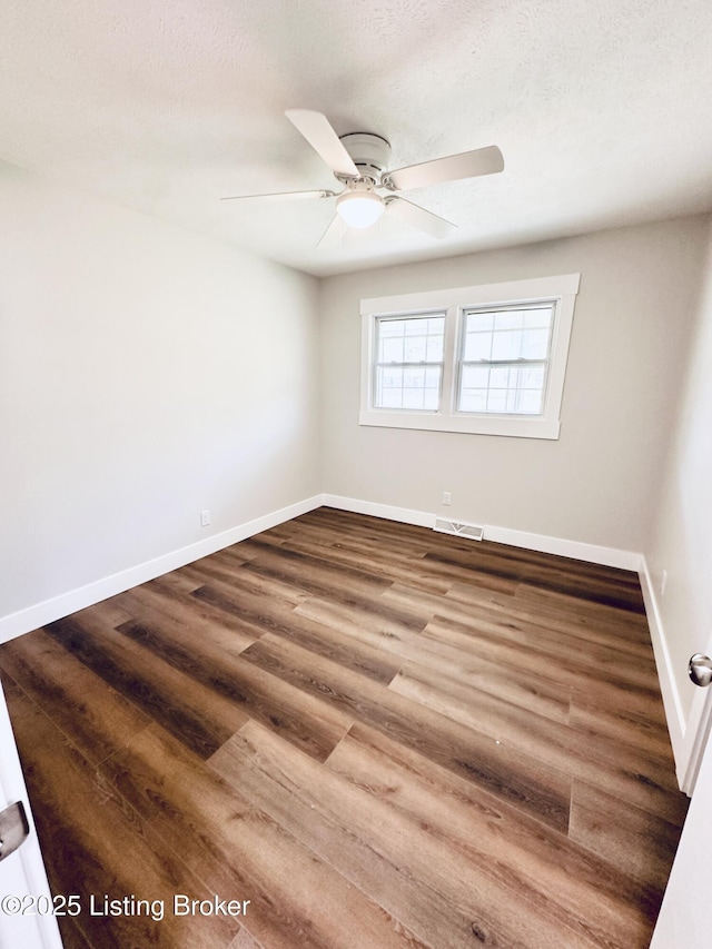spare room with baseboards, visible vents, wood finished floors, and a ceiling fan