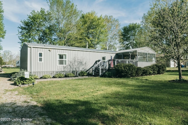 manufactured / mobile home featuring board and batten siding, metal roof, a sunroom, and a front lawn
