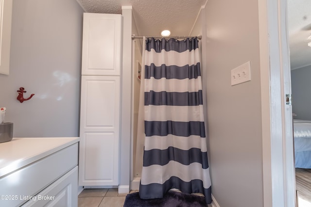 full bath with tile patterned flooring, a textured ceiling, a shower with curtain, and vanity