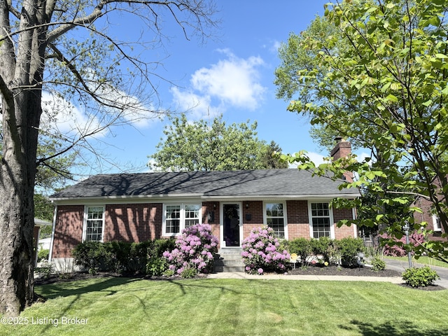 ranch-style house featuring a chimney, a front yard, and brick siding