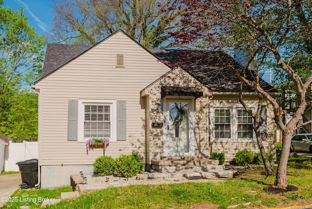 view of front facade featuring entry steps, fence, and a shingled roof