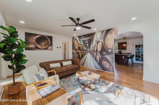 living area with recessed lighting, arched walkways, ceiling fan, and wood finished floors