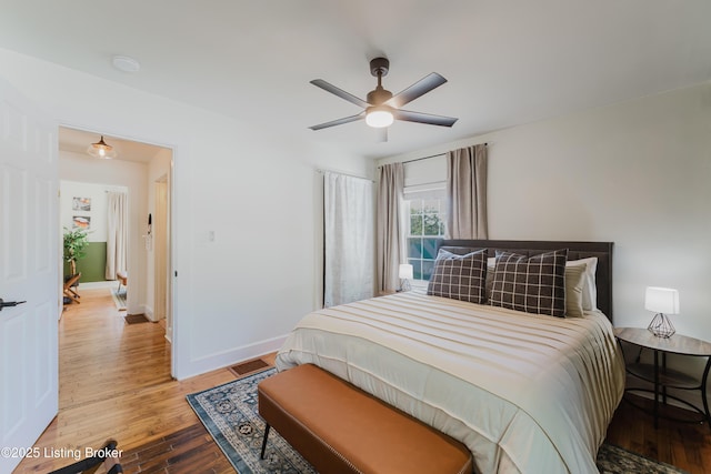 bedroom featuring visible vents, baseboards, ceiling fan, and wood finished floors