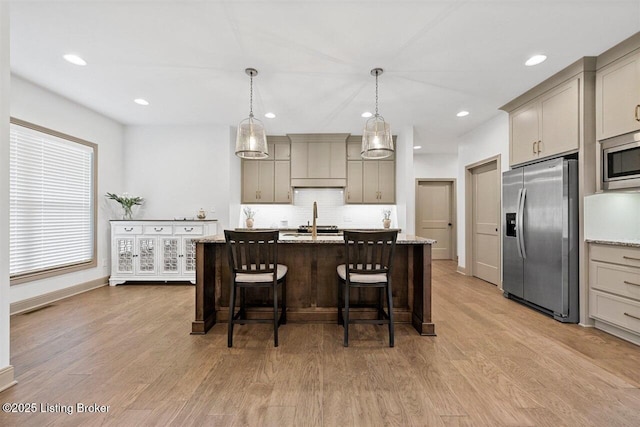 kitchen with a sink, decorative backsplash, stainless steel appliances, and light wood-type flooring