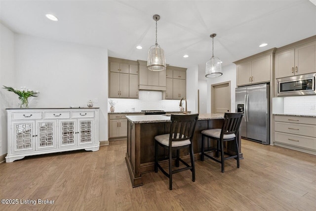 kitchen with recessed lighting, a center island with sink, tasteful backsplash, and stainless steel appliances