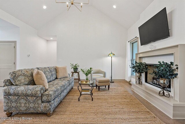 living room featuring an inviting chandelier, high vaulted ceiling, recessed lighting, and wood finished floors