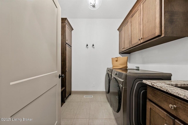 washroom with baseboards, visible vents, cabinet space, and washer and dryer