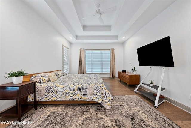 bedroom featuring wood finished floors, baseboards, recessed lighting, a raised ceiling, and a ceiling fan