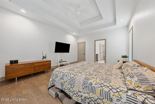bedroom featuring recessed lighting, a ceiling fan, wood finished floors, and a tray ceiling