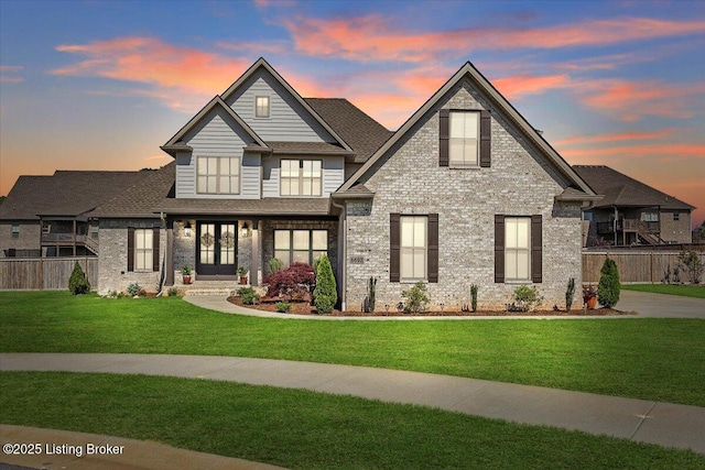 craftsman inspired home with a lawn, brick siding, fence, and a shingled roof
