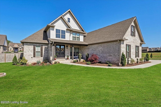 back of property with brick siding, a lawn, and roof with shingles