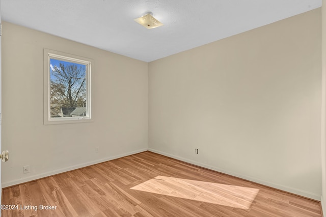 spare room with baseboards and light wood-type flooring