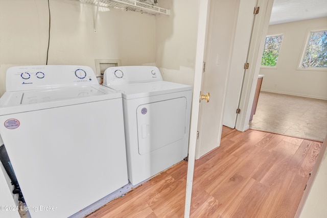 washroom with laundry area, washer and clothes dryer, light wood finished floors, and baseboards