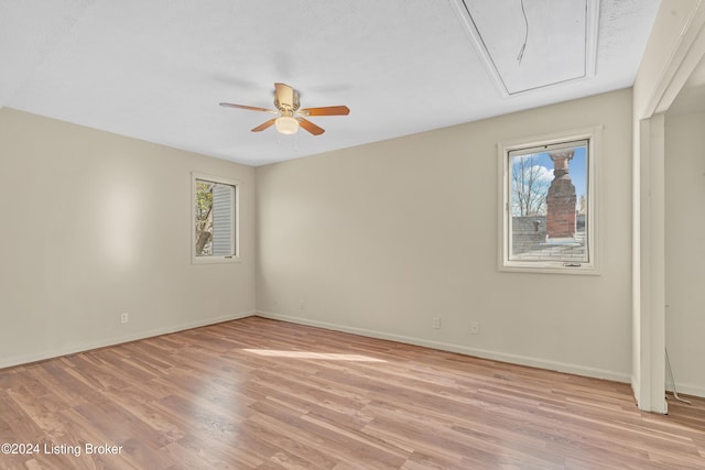 unfurnished room with plenty of natural light, attic access, and light wood-style flooring