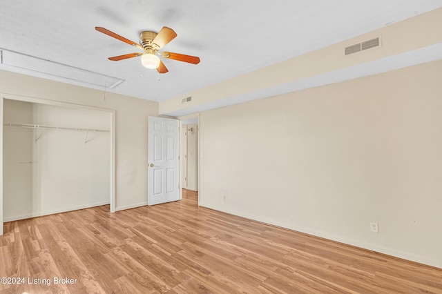 unfurnished bedroom featuring a closet, attic access, light wood finished floors, and visible vents