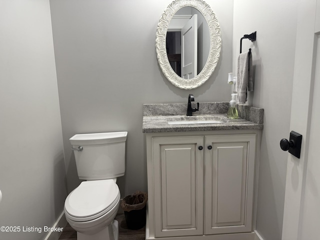 bathroom with toilet, vanity, and baseboards