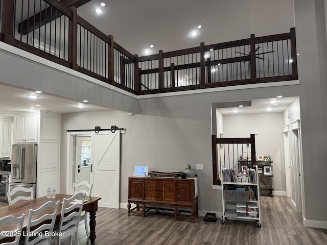 living room featuring a barn door, a high ceiling, wood finished floors, and baseboards