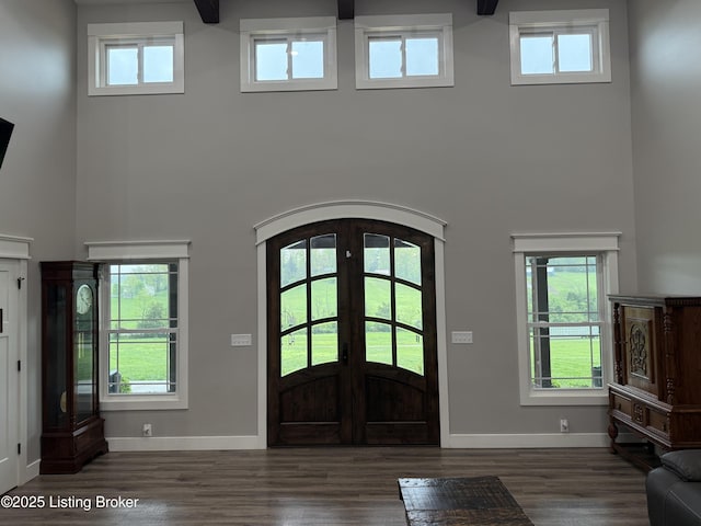 foyer entrance with french doors, baseboards, arched walkways, and a high ceiling