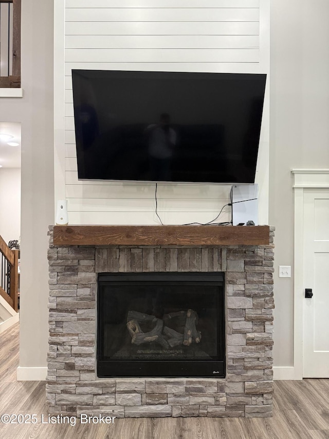 interior details with a stone fireplace, wood finished floors, and baseboards