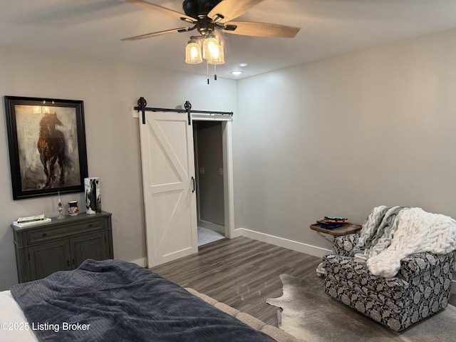 bedroom with ceiling fan, wood finished floors, a barn door, and baseboards