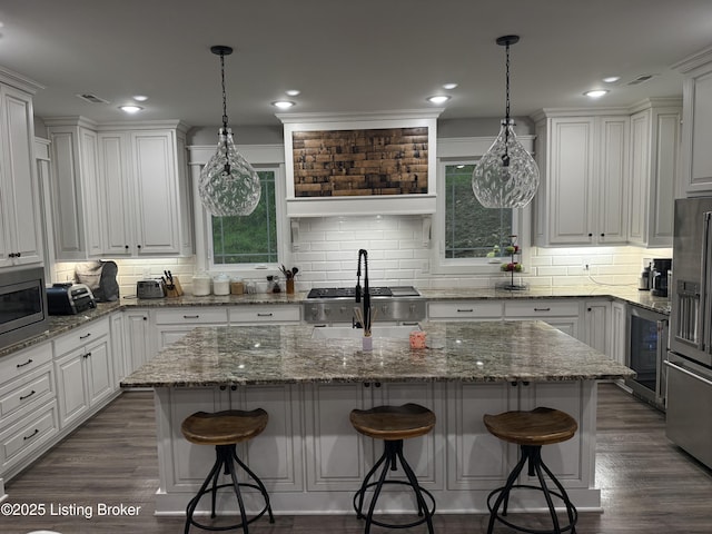 kitchen with beverage cooler, tasteful backsplash, a kitchen island with sink, stainless steel appliances, and white cabinets