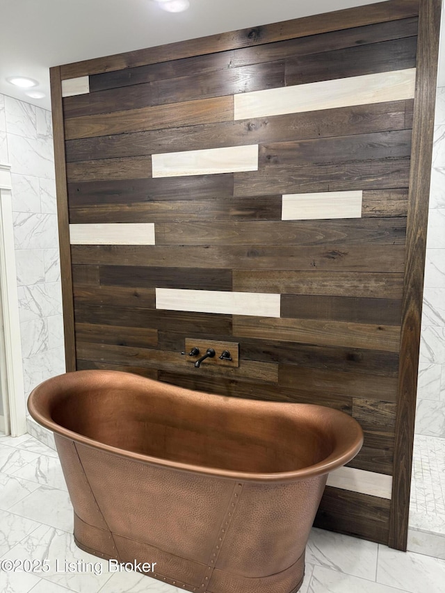 bathroom featuring wooden walls, recessed lighting, marble finish floor, and a freestanding bath