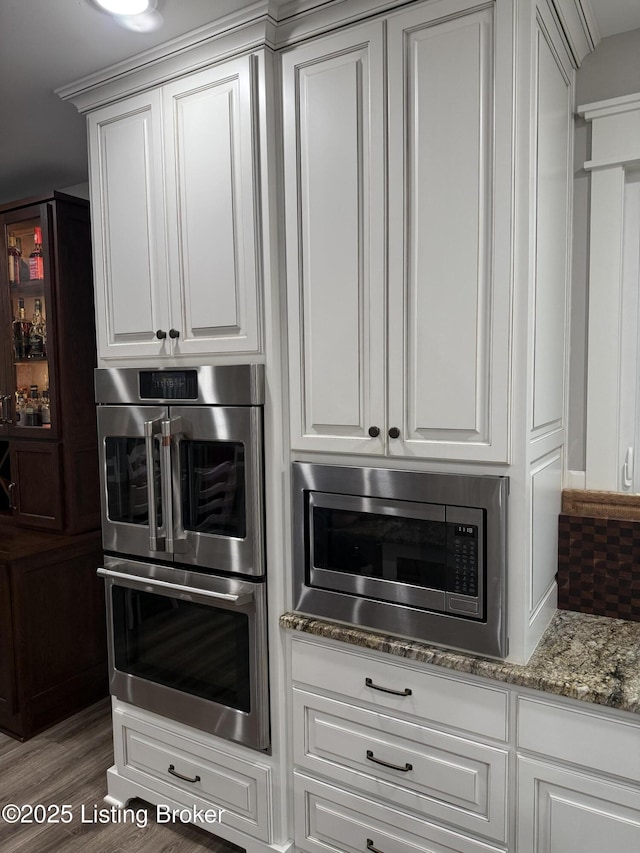 kitchen featuring light stone countertops, stainless steel appliances, and white cabinets