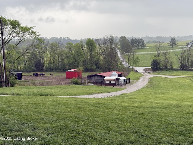 surrounding community featuring fence, a rural view, a pole building, an outbuilding, and a lawn
