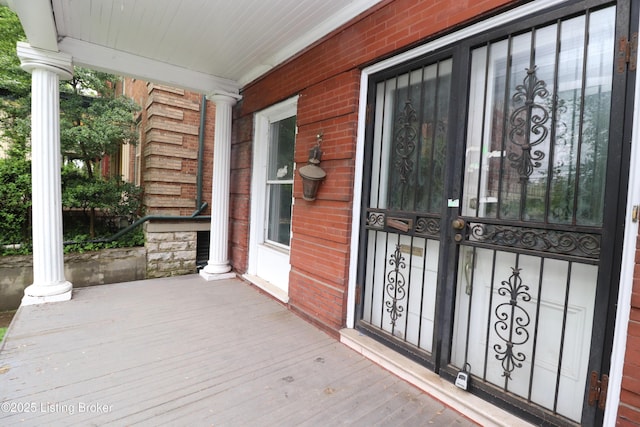 doorway to property featuring covered porch and brick siding