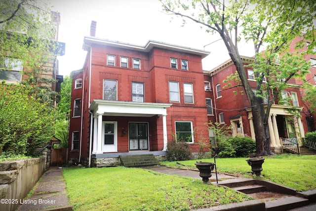 view of front of property with covered porch, a front yard, and brick siding