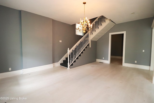 spare room featuring baseboards, stairway, wood finished floors, and an inviting chandelier