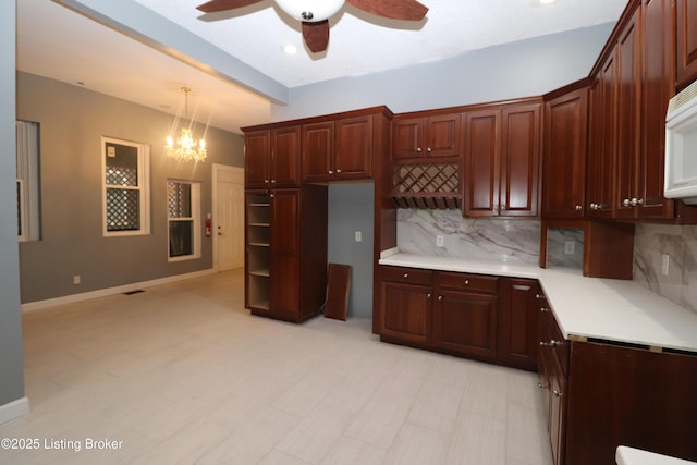 kitchen with decorative backsplash, baseboards, light countertops, hanging light fixtures, and ceiling fan with notable chandelier