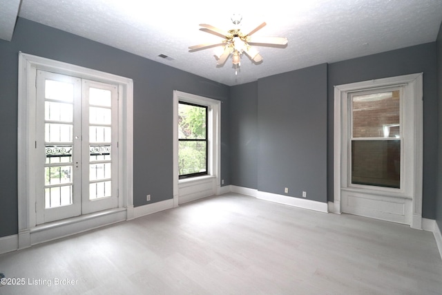 empty room with visible vents, wood finished floors, french doors, and baseboards