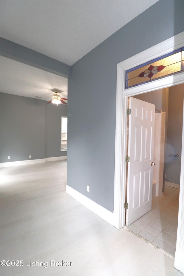 empty room featuring baseboards, wood finished floors, and a ceiling fan