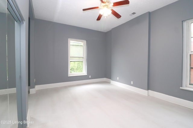 spare room with wood finished floors, ceiling fan, visible vents, and baseboards