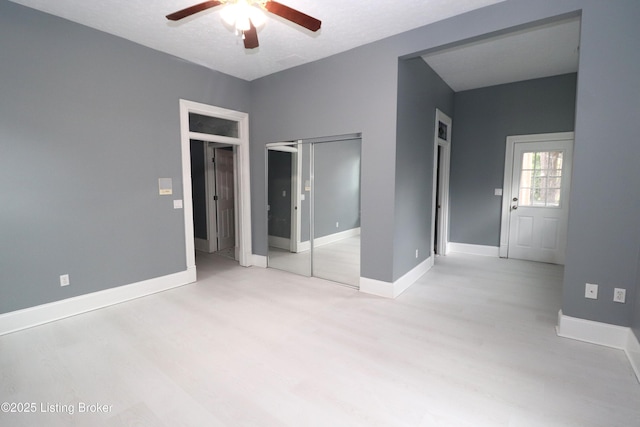 unfurnished bedroom featuring wood finished floors, ceiling fan, baseboards, and a closet