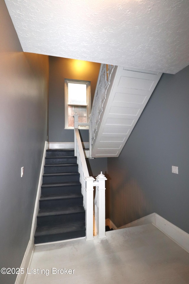 staircase with a textured ceiling and baseboards