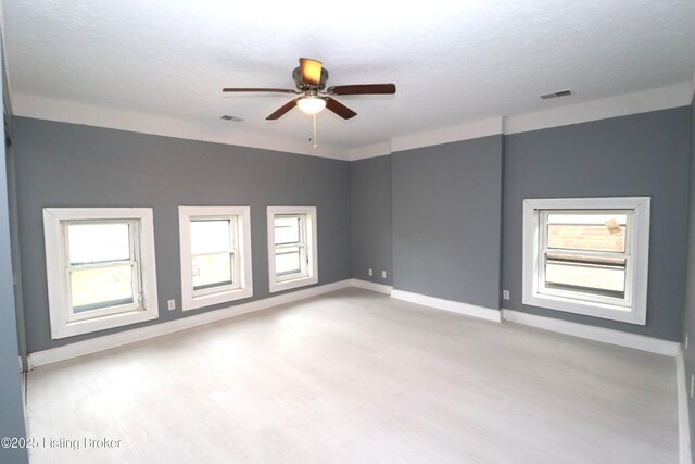 unfurnished room featuring baseboards, visible vents, wood finished floors, and a ceiling fan