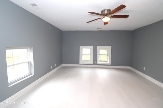spare room with light wood-style floors, a ceiling fan, and baseboards