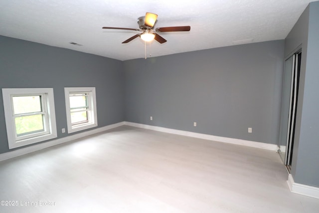 spare room with baseboards, visible vents, a ceiling fan, and light wood finished floors