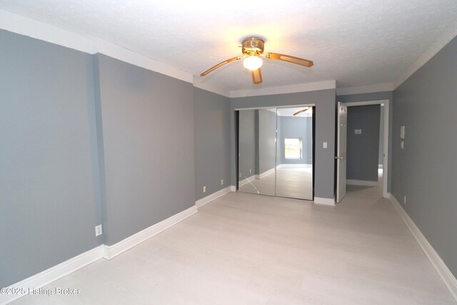 unfurnished bedroom featuring a ceiling fan, light wood-style flooring, a textured ceiling, and baseboards