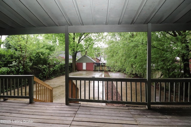wooden terrace featuring a fenced backyard, a shed, and an outbuilding
