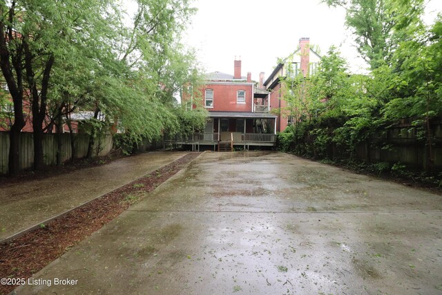 rear view of house with covered porch, fence, and a chimney