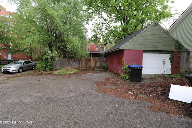 ranch-style house featuring an outbuilding, a detached garage, roof with shingles, and fence