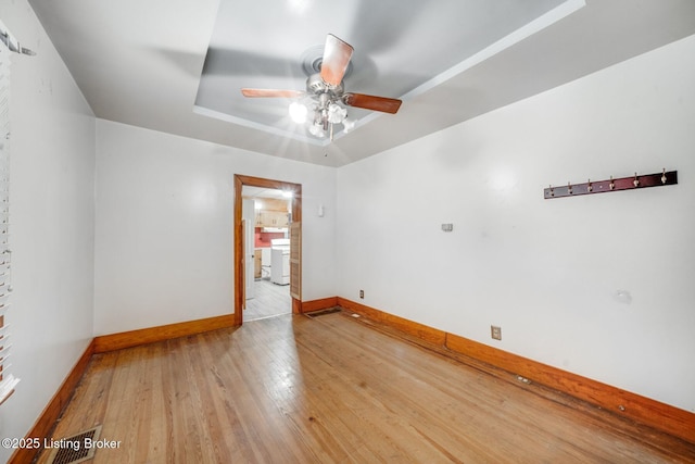 empty room featuring light wood finished floors, a ceiling fan, and baseboards